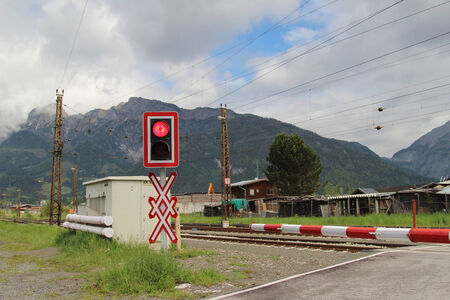 Railroad crossing with a red warning sign in Austrian Alps