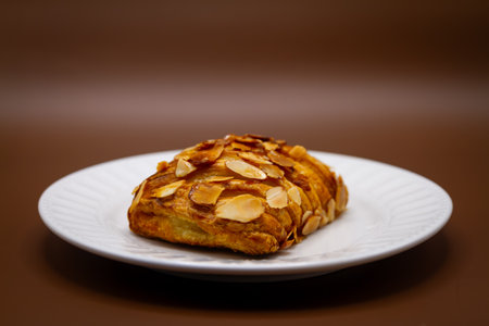 Closeup of almond croissant on white plate on brown backgroundの写真素材