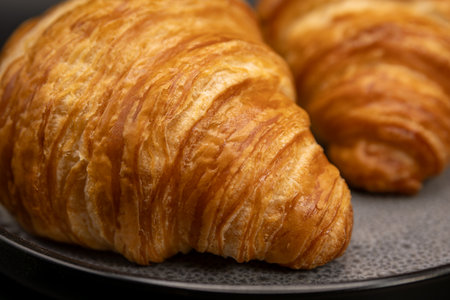Freshly baked croissants on a black plate, close upの写真素材