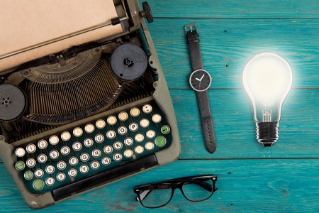 Idea concept - bulb, Vintage typewriter, watches and glasses on the blue wooden deskの写真素材