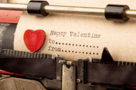 Happy Valentine`s day - phrase on typewriter. Valentines day greetings concept. Little red wooden heart close up. Valentine's greeting card.の写真素材