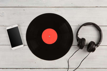 Vintage record LP, smartphone and headphones on the wooden background