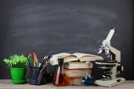 Education concept - books and microscope on the desk in the auditorium