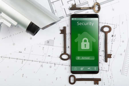 Home security concept - smartphone with smart home app and surveillance cctv camera on the deskの写真素材