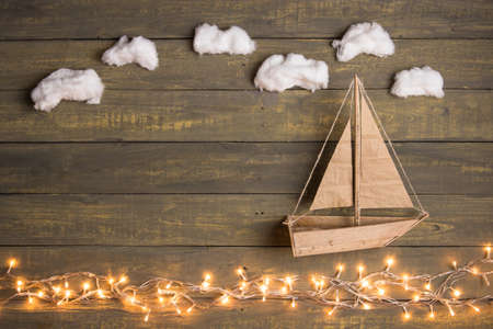 Travel and adventure creative concept - toy boat on a wooden background with cotton clouds....