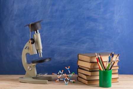 Education and sciences concept - books on the teacher desk in the auditorium, chalkboard on the...
