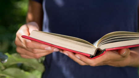 Reading and education in summer concept, girl holding an open book, reading outdoors in a garden