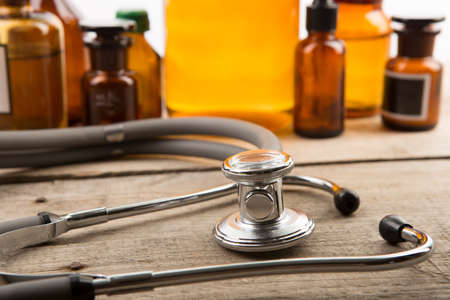 Workplace of doctor - stethoscope and pharmacy bottles on the wooden deskの写真素材