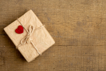 Valentine's Day greetings concept. Little red wooden crafted heart and gift box close up on the...