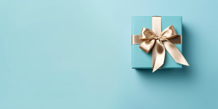 Gift box with satin ribbon and bow on blue background.の素材