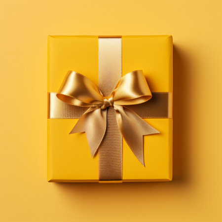 Gift box with golden satin ribbon and bow on yellow backgrounの素材