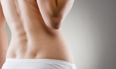 Part of female back with scoliosis over grey. Back or spine injury and treatment.の写真素材