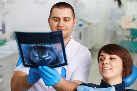 Doctor hygienist and female patient looking at jaw x-ray in dentist office. Concept of healthy teeth and cavity protection.の写真素材