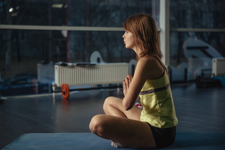 Yoga. Meditation. Young sporty female relaxing in prayer position in the gym.の写真素材