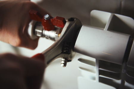 Male technician fixing radiator in the room. Concept of repair, maintenance and control.