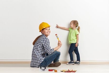 Young family repairing their accommodation. Cute girl pointing at the wall for painting.の写真素材