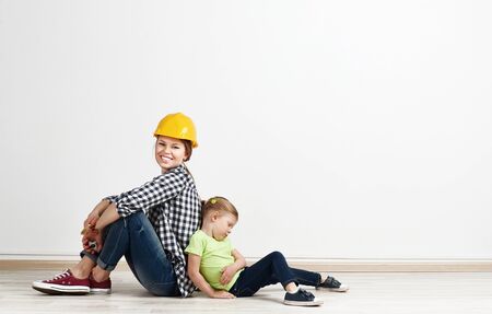 Portrait of tired child and smiling mum after home reparation. Concept of new house purchase and relocation.の写真素材