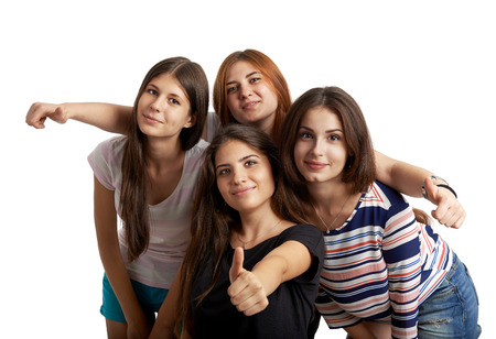 Studio portrait of pretty teenage girls embracing, showing thumbs up over white background. Concept of team, success and confidence.の写真素材