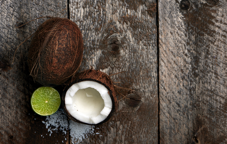 Macro shoot of broken coconut and lime on wooden background with blank space. Healthy food and diet concept.の写真素材