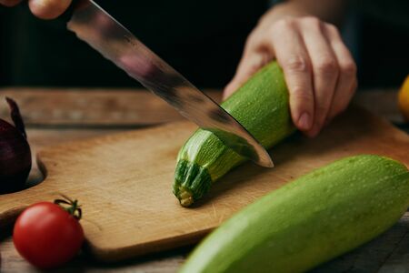 Macro shot of chef cutting fresh raw zucchini on board in the kitchen.の写真素材