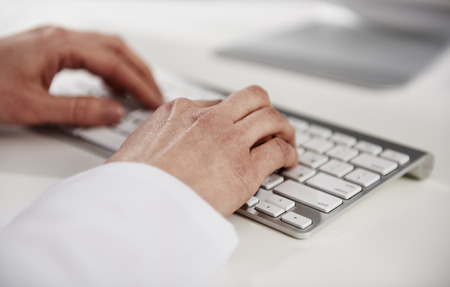 Woman practitioner typing medical report on keyboard at the desk.の写真素材