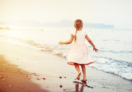 Summer vacation. Little child running barefoot on the sand on seacoast.の写真素材