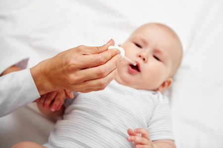 Portrait of baby girl getting vaccine drops in clinic. Health care and therapy concept.の写真素材