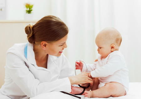 Woman doctor doing medical examination of little baby girl in hospital.の写真素材