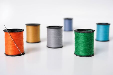 Colorful spools of thread scattered about with a needle.の写真素材