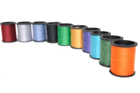 Colorful spools of thread stacked on white.