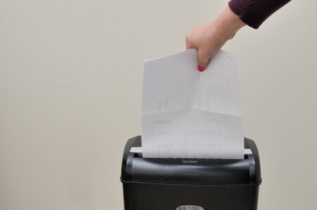 Hand putting paper into a shredderの写真素材