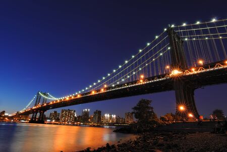 The Manhattan Bridge illuminated at night spanning the East River in New York city.の写真素材