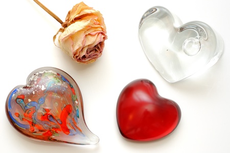 Glass paperweight hearts and a dried rose on whiteの写真素材