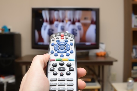 TTelevision remote in the foreground with selective focus and television in the background.のeditorial素材