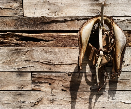 Odl worn saddle hanging from an old barn wallの写真素材