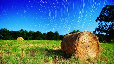 Moonlit hay bale under star trails on a farm in North Georgia, USA.