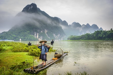 Cormorant fisherman and his birds on the Li River in Yangshuo, Guangxi, China の写真素材