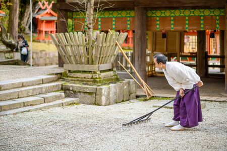 NARA, JAPAN - NOVEMBER 18, 2012: A Shinto Priest rakes a gravel Zen Garden at Kasuga-Taisha Shrine. The gardens have a long history in Japan and the surroundings are used to aid meditation.のeditorial素材
