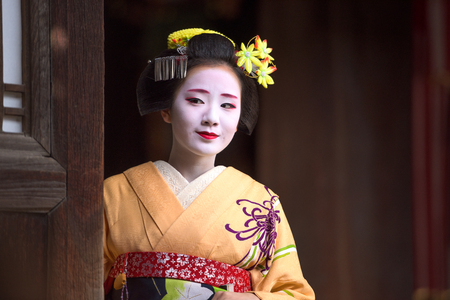 KYOTO, JAPAN - NOVEMBER 28, 2015: A woman dressed as a traditional Maiko looks out of a temple doorway.のeditorial素材