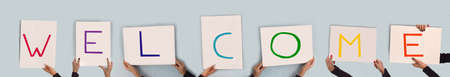 colorful word Ã©welcome on seven white blank rectangular signs hold by women's hands, panoramic...