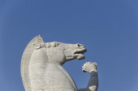 Modern sculpture of horse in front of a symbol of Romeの写真素材