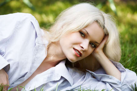 Happy young woman has a rest on the nature with shining smileの写真素材