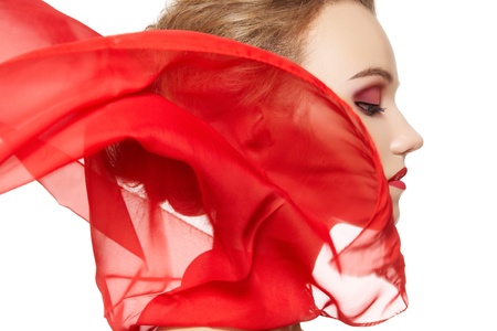 Fashionable portrait of a girl model with waving red silk scarf. Fashion, glamour accessories, evening makeup. Freedom vamp bright style, lady in red on white background の写真素材