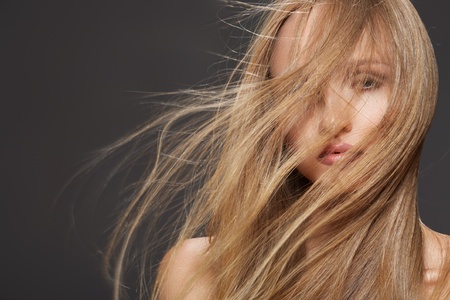 Wellness and spa. Sensual woman model with winswept flying dark blond hair on gray background. Shiny long health hairstyle. Beauty and haircare の写真素材