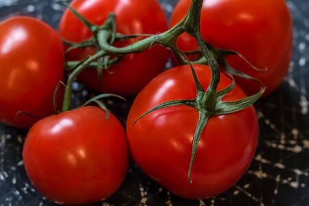 Red tomatoes on a green branch Ð°re placed on a black and white background. Close-up. Vegetables Close-up. Vegetablesの写真素材