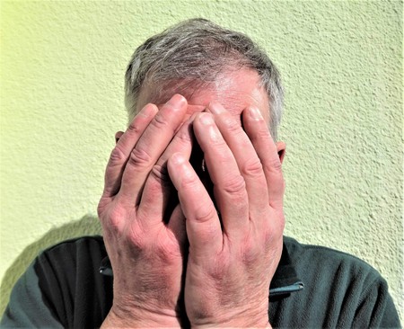 A man's face covered by his hands show emotion