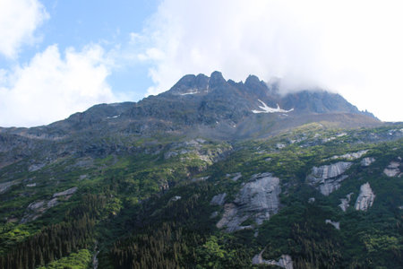 Clouds hanging over the top of a rugged mountain in Southern Alaskaの写真素材