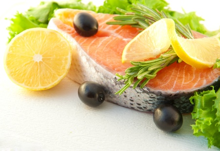 Salmon with a lemon, olives and rosemary on a white backgroundの写真素材