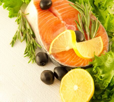 Salmon with a lemon, olives and rosemary on a white backgroundの写真素材