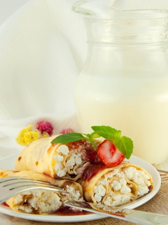 Fritters with strawberry jam and mint and a jug with milkの写真素材